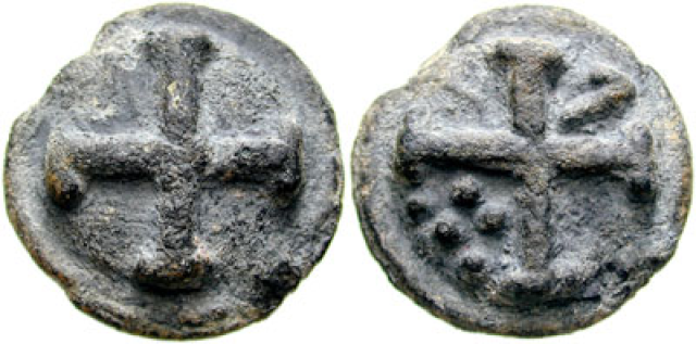Pictures of the two sides of an ancient, corroded, worn, weathered coin.  Each one has a four-armed cross who arms have crossbars at the ends, and the one on the right also has five dots.  The dots are in a cluster in the space between the cross's lower and left arms, and are arranged in a row of three and, closer to the center, a row of two.
